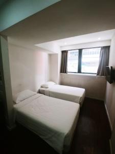 two beds in a hotel room with a window at Homy Central in Hong Kong