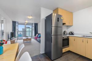 a kitchen with a stainless steel refrigerator and a living room at Wonderful Apartment in Quiet CBD Neighbourhood! in Auckland