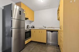 a kitchen with yellow cabinets and a stainless steel refrigerator at Wonderful Apartment in Quiet CBD Neighbourhood! in Auckland