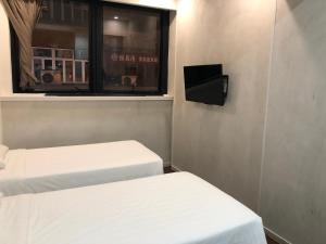 a small room with two beds and a window at Homy Central in Hong Kong