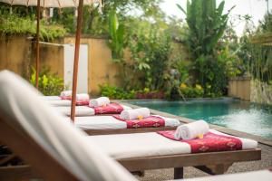 a row of chaise lounges next to a swimming pool at Swahita Ubud in Ubud
