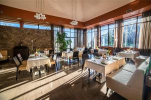 un restaurante con mesas, sillas y ventanas grandes en Hotel Irys by Derenivska Kupil en Nyzhne Solotvyno