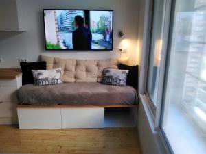 a living room with a couch with a tv on the wall at L' établissement APPARTEMENTS DESIGN , vous propose 4 appartements neufs avec services , NETFLIX , lits faits à votre arrivée , serviettes de toilette , ménage, Wifi , en hyper centre , Vue mer à 200m , BOX à Vélos sur demande in Dieppe