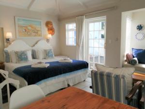 Schlafzimmer mit einem Bett, einem Schreibtisch und einem Fenster in der Unterkunft Eastbury Cottage in Hermanus