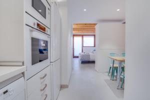 a kitchen with white cabinets and a dining room with a table at Urban Suites Palma - Turismo de Interior by PriorityVillas in Palma de Mallorca +37 photos