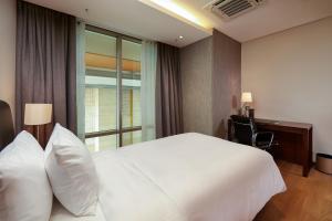 um quarto de hotel com uma grande cama branca e uma secretária em Lotte The Residence em Hanói