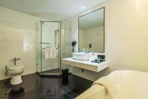y baño con lavabo, aseo y ducha. en Merlynn Park Hotel, en Yakarta
