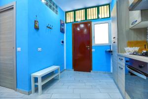 a blue kitchen with a red door and a bench at Da Zia Geppina in Naples