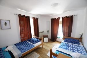 two beds in a room with two windows at ODEON Apartment And Rooms in Rijeka