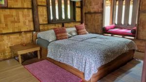 Schlafzimmer mit einem Bett, einem Tisch und Fenstern in der Unterkunft Sang Tong Huts in Mae Hong Son