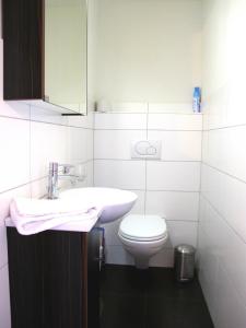 a white bathroom with a sink and a toilet at Bergquelle Dachwohnung in Bettmeralp