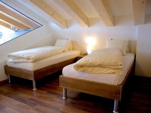 Cette chambre mansardée comprend 2 lits jumeaux et une fenêtre. dans l'établissement Bergquelle Dachwohnung, à Bettmeralp