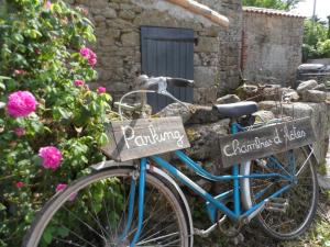 Una bicicleta azul estacionada en un jardín con letreros. en Les chambres du Couraud en Saint-Aubin-des-Ormeaux