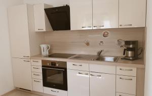 a small kitchen with white cabinets and a sink at Ferienwohnung Angelina in Markdorf +6 photos