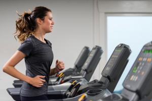 巴勒納紹的住宿－布魯爾斯運動酒店，一名在健身房跑步机上跑步的女人