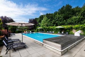 a swimming pool with chairs and an umbrella at Sporthotel Bruurs in Baarle-Nassau