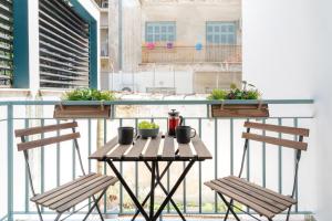 a balcony with two chairs and a table with plants on it at Athena by Heloni Apartments in Athens