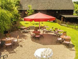 a patio with tables and chairs and a red umbrella at Stöltings Landhaus in Wiehl