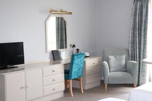 a bedroom with a dresser with a tv and two chairs at Causeway Hotel in Bushmills
