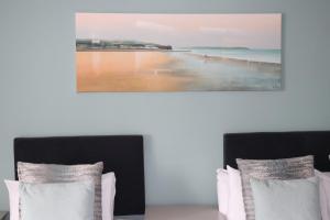 two beds in a room with a picture of a beach at Causeway Hotel in Bushmills