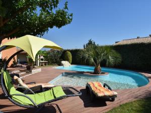 einen Pool mit Stühlen und einem Sonnenschirm in einem Hof in der Unterkunft Luxury holiday home with private pool in Rodilhan