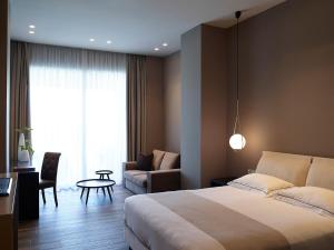 a bedroom with a bed and a couch and a chair at Pelagos Suites Hotel & Spa in Kos