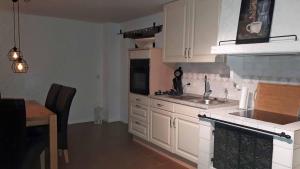 eine Küche mit weißen Schränken und einem Waschbecken und einem Tisch in der Unterkunft Sissi's Feriendomizil in Winterberg
