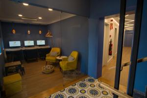 a waiting room with yellow chairs and a table at ZIGZAG HOSTEL in Praia da Vitória