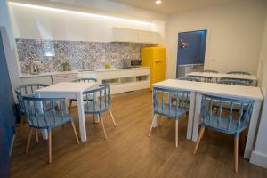 a kitchen with white tables and blue chairs at ZIGZAG HOSTEL in Praia da Vitória