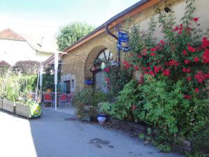 a house with red flowers on the side of it at Chambres d'Hôtes Pom' Paille in Pupillin