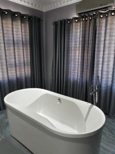 a white bath tub in a bathroom with black curtains at The Green Olive Guesthouse in Bethlehem