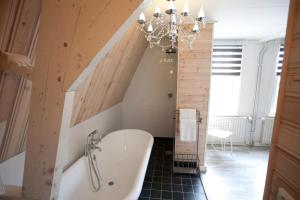 a bathroom with a bath tub and a chandelier at Sonop in Oostkapelle +47 photos