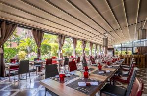 restauracja ze stołami i krzesłami oraz dużymi oknami w obiekcie Hivernage Hotel & Spa w Marakeszu