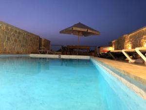 a swimming pool with an umbrella and chairs at Villa Lyons in Żejtun