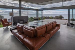 a brown leather couch in a living room with a fireplace at Avalon Coastal Retreat in Swansea