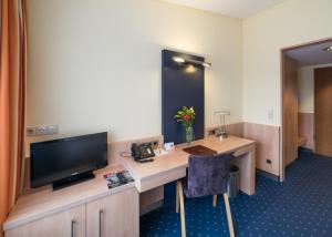a hotel room with a desk with a tv and a desk sidx sidx sidx sidx at Hotel Gustav-Stresemann-Institut in Bonn