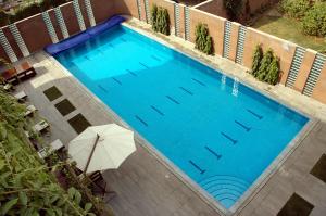 an overhead view of a large swimming pool with an umbrella at The Residency Hotel in Lahore