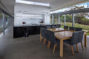 an open kitchen and dining room with a wooden table and chairs at Avalon Coastal Retreat in Swansea +18 photos