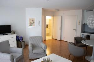 ein Wohnzimmer mit einem Sofa, Stühlen und einem TV in der Unterkunft Senioren-Residenz Segeten in Zürich