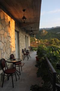 een patio met tafels en stoelen en een stenen muur bij Studio and winery Kalimut in Virpazar