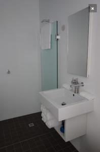 a white bathroom with a sink and a shower at Avalon Coastal Retreat in Swansea