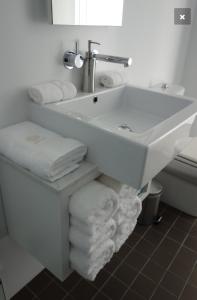 a white bathroom with a sink and towels at Avalon Coastal Retreat in Swansea