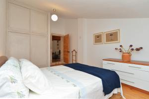 a white bedroom with a bed and a dresser at House Silvo 1953 in Vodnjan