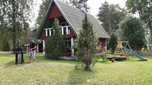 a man standing in front of a red house with a playground at Holiday Home with Sauna in Kassari