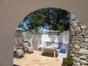 un patio avec une table et des chaises et un mur en pierre dans l'établissement Casa Pura Vida - fantastic sea view, à Pêra