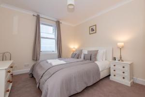 a white bedroom with a large bed and a window at Achaniar Cottage in St. Andrews