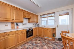 uma cozinha com armários de madeira e uma mesa em Achaniar Cottage em St Andrews