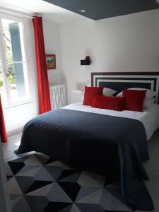 Un dormitorio con una cama con almohadas rojas y una ventana en coté remparts, en Provins