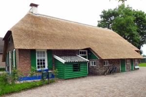 a small brick house with a thatched roof at Vakantiehuis An Diek in Staphorst