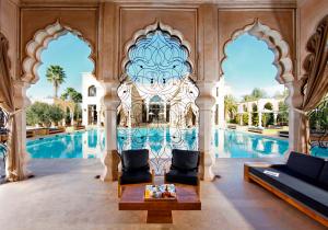 einen Pool in einem Palast mit zwei Stühlen und einem Tisch in der Unterkunft Palais Namaskar in Marrakesch